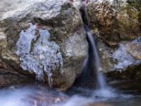 Rinnsal zwischen Steinen mit kleineren Eisfiguren